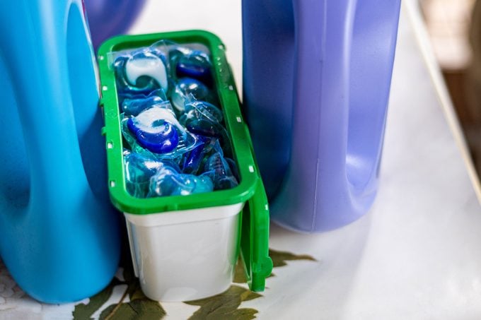 bottes of laundry detergent and laundry pods on top of a washing machine