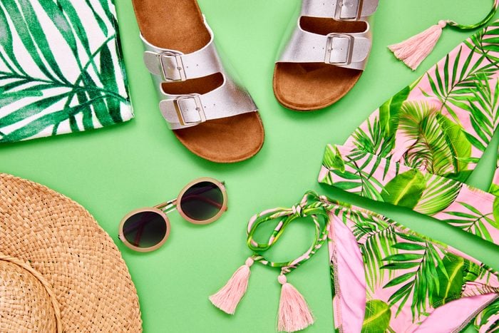 Overhead shot of summer vacation accessories on green background